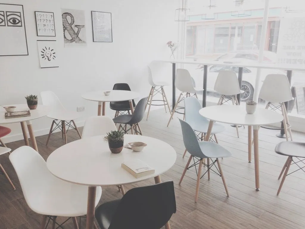 Quán cafe tông sáng với bàn tròn và ánh sáng cửa sổ